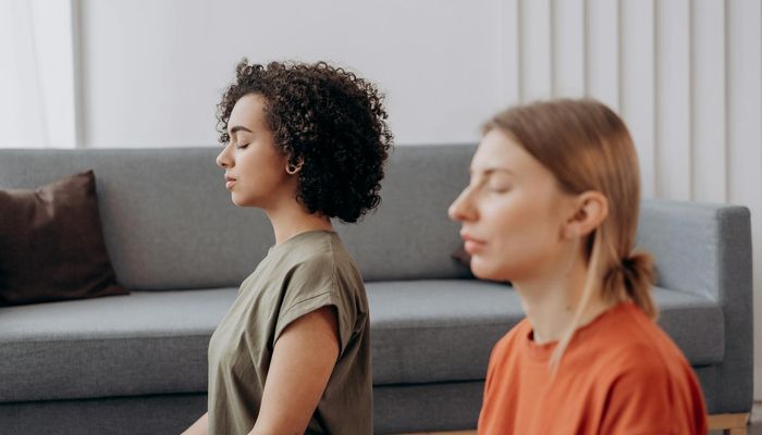A serene woman meditating in a lotus position in a beautifully lit room.