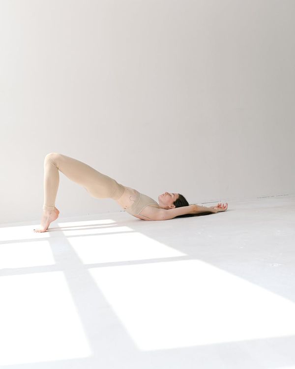 Woman in a calm yoga pose, demonstrating flexibility and balance indoors.